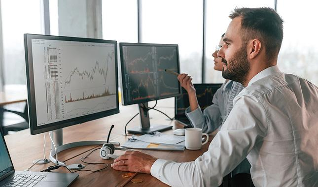 Financial performance charts on multiple monitors